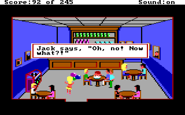 The cops sit around a table in the bar. Jack is face down in his birthday cake. A blonde white woman in a tiny yellow bikini enters holding balloons and swinging her ass. Game text reads: "Jack says, 'Oh no! Now what?!'"