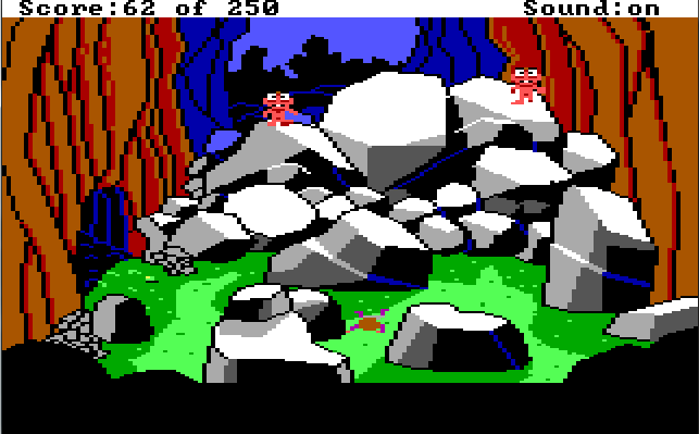 At the bottom of the ravine. There is a cave opening to the left and a large pile of boulders in the middle of the screen. Two small pink aliens with big eyes stand on the boulders. Roger lies face down on the ground in front of them.