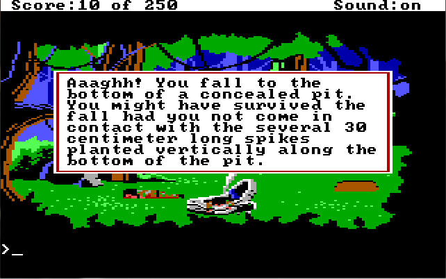 The same forest scene, but there is now a hole in the ground on the right side of the screen. Game text: "Aaaghh! You fall to the bottom of a concealed pit. You might have survived the fall had you not come in contact with the several 30 centimeter long spikes planted vertically along the bottom of the pit."