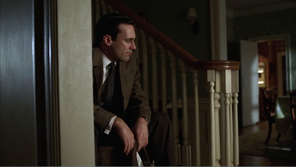 The last shot of the episode. Don sits on the stairs of his house, holding his hat. The room is dark. He is partially obscured by the wall by the stairs. 