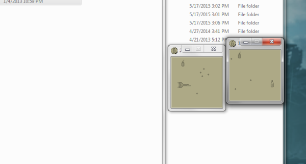 Milk! screenshot. A Windows desktop with some folders open. To the right are two small windows both showing a simple monochrome game. One window has a spaceship in it. There are milk bottles, bombs, and obstacles placed randomly around both windows.