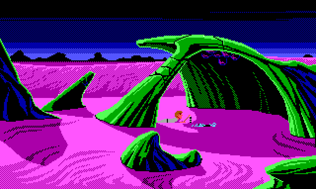 An area where curved green rock formations jut out of the purple dunes. One formation forms a wide arch, at the top of which are some dark purple blob-shaped growths. Underneath, Roger lies on his stomach and picks up some object from a metallic pile with a stick.